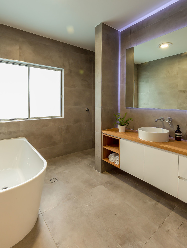 Idéer för ett stort modernt badrum, med skåp i ljust trä, ett fristående badkar, en öppen dusch, grå kakel, grå väggar, träbänkskiva och med dusch som är öppen