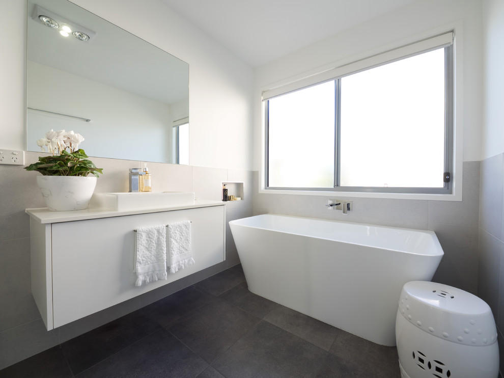 Inspiration for a large contemporary family bathroom in Brisbane with white cabinets, a freestanding bath, a corner shower, grey tiles, ceramic tiles, white walls, ceramic flooring, a wall-mounted sink and granite worktops.