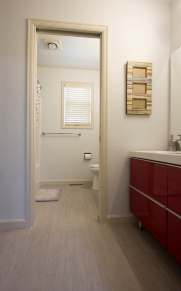 Idées déco pour une salle de bain moderne de taille moyenne pour enfant avec un lavabo intégré, un placard à porte plane, des portes de placard rouges, un plan de toilette en surface solide, une baignoire posée, WC à poser, un carrelage gris, mosaïque, un mur gris et un sol en carrelage de porcelaine.