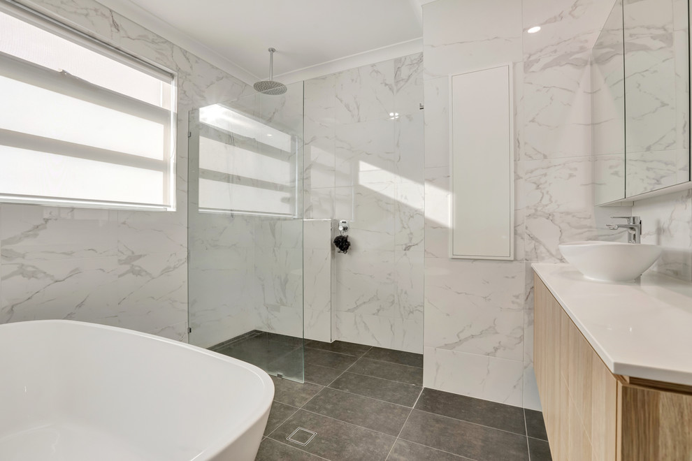 Idée de décoration pour une grande salle de bain design en bois clair avec une baignoire indépendante, une douche double, un carrelage blanc, des carreaux de céramique, un sol en carrelage de céramique, un plan de toilette en surface solide, un sol marron et un plan de toilette blanc.