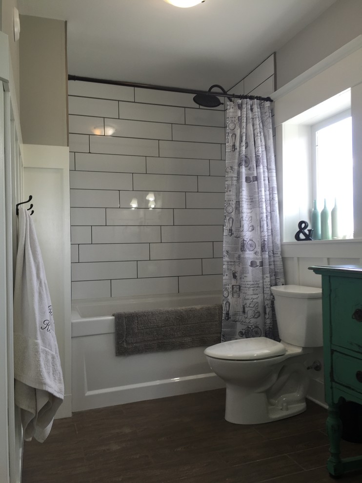 Пример оригинального дизайна: ванная комната среднего размера в стиле кантри с фасадами островного типа, бирюзовыми фасадами, ванной в нише, душем над ванной, раздельным унитазом, белой плиткой, керамической плиткой, серыми стенами, полом из керамической плитки, накладной раковиной, столешницей из дерева, серым полом, шторкой для ванной, бирюзовой столешницей, нишей, тумбой под одну раковину, напольной тумбой и панелями на стенах