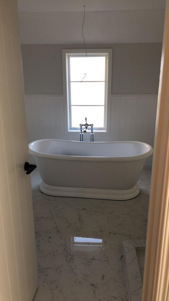 Photo of a medium sized victorian ensuite bathroom in Auckland with shaker cabinets, white cabinets, a freestanding bath, a corner shower, a one-piece toilet, beige walls, ceramic flooring, a vessel sink, marble worktops, white floors, an open shower, white worktops, double sinks, a floating vanity unit, a vaulted ceiling and tongue and groove walls.