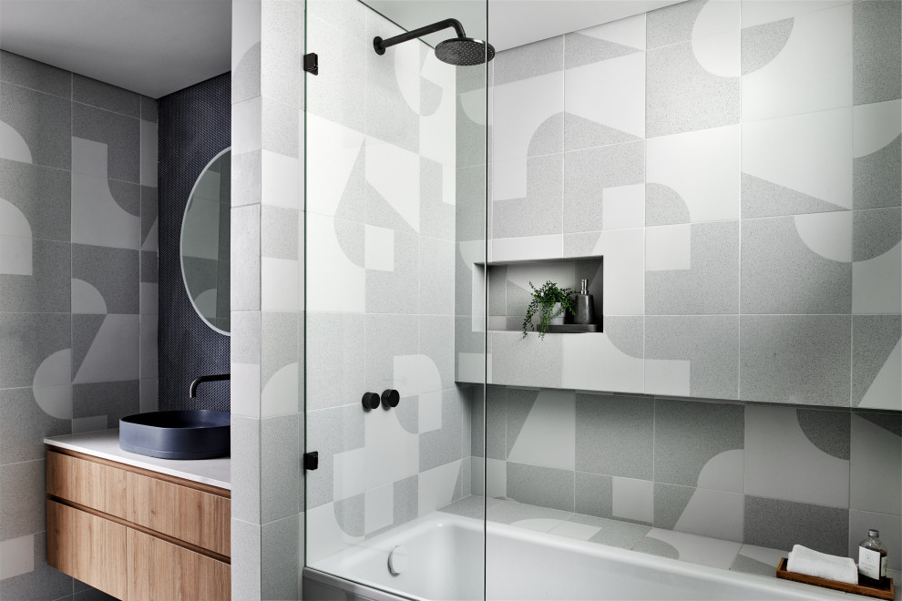 Exempel på ett mellanstort skandinaviskt badrum, med skåp i mellenmörkt trä, ett platsbyggt badkar, en dusch/badkar-kombination, blå kakel, porslinskakel, klinkergolv i porslin, ett fristående handfat, bänkskiva i kvarts och grått golv