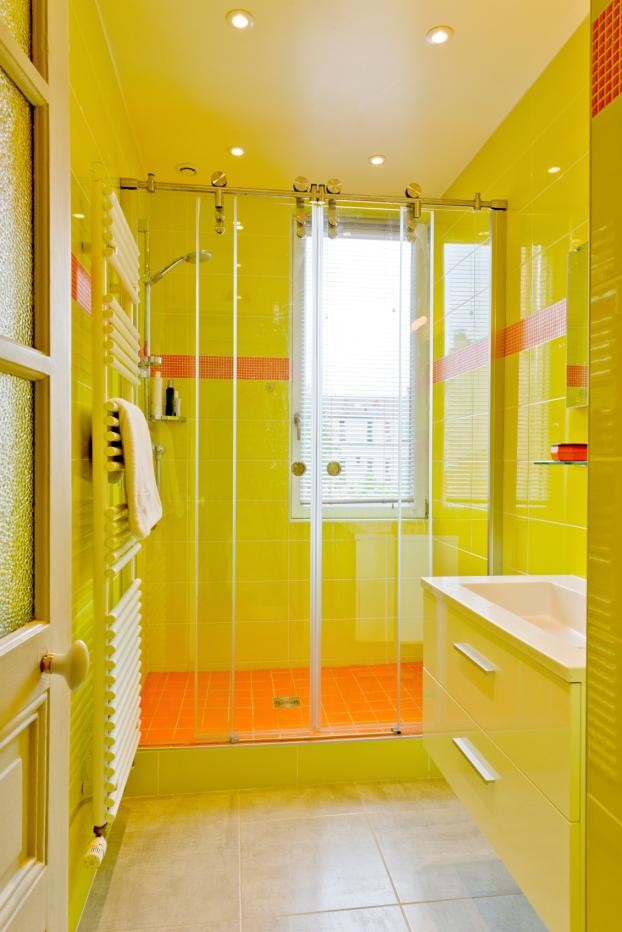 Immagine di una stanza da bagno eclettica con ante lisce, ante gialle, doccia alcova, pareti gialle, pavimento in gres porcellanato e top in quarzo composito