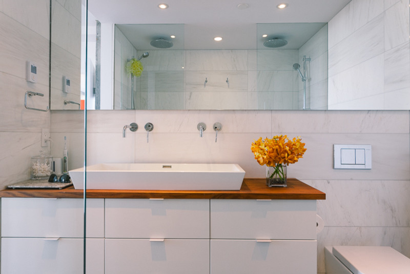 Bathroom - mid-sized modern 3/4 white tile and marble tile slate floor and brown floor bathroom idea in Vancouver with flat-panel cabinets, white cabinets, wood countertops, a wall-mount toilet, white walls, a trough sink and brown countertops