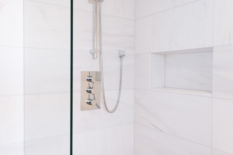 Example of a mid-sized minimalist 3/4 white tile and marble tile slate floor and brown floor bathroom design in Vancouver with white walls, flat-panel cabinets, white cabinets, a wall-mount toilet, a trough sink, wood countertops and brown countertops