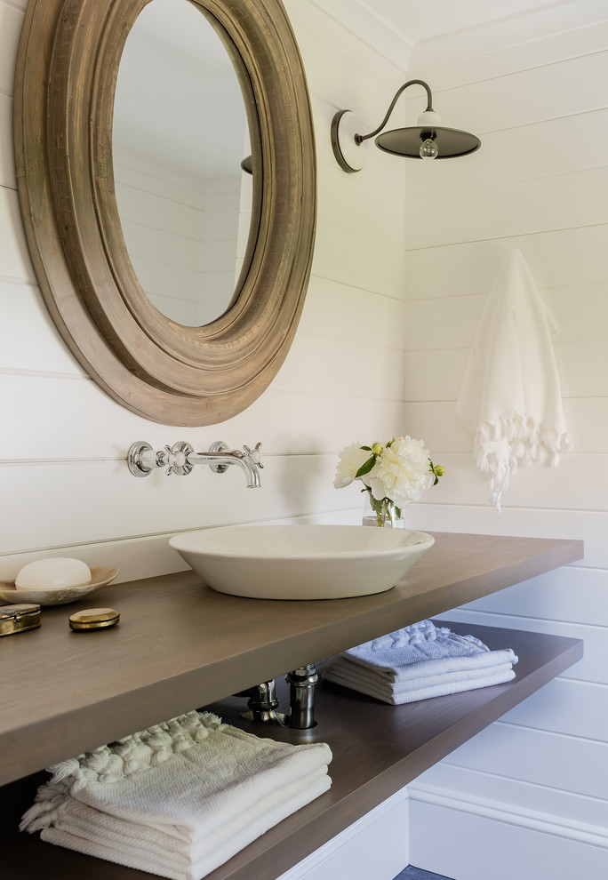 Imagen de cuarto de baño marinero con armarios abiertos, paredes blancas, lavabo suspendido, encimera de madera y encimeras marrones