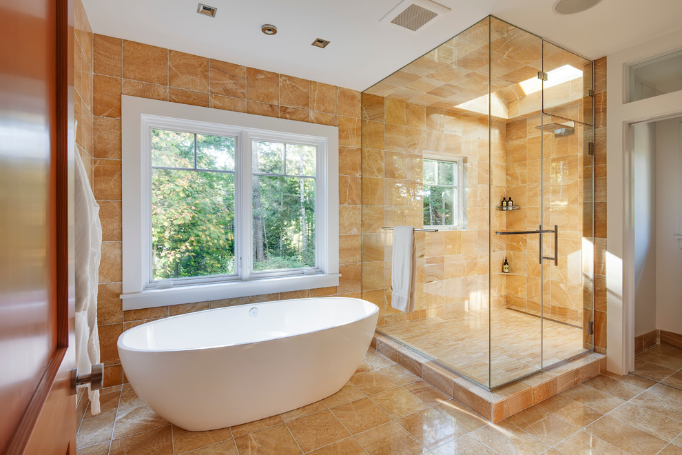 Пример оригинального дизайна: большая главная ванная комната в современном стиле с отдельно стоящей ванной, угловым душем, бежевой плиткой, унитазом-моноблоком, керамогранитной плиткой, бежевыми стенами, мраморным полом, настольной раковиной, плоскими фасадами, светлыми деревянными фасадами и столешницей из искусственного камня