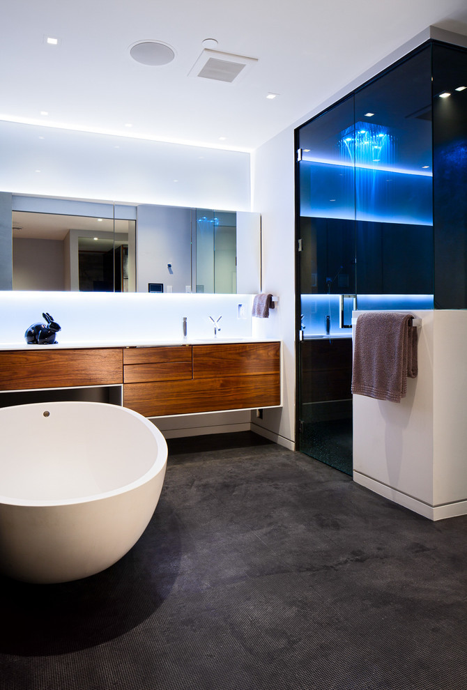 Large contemporary ensuite bathroom in Vancouver with flat-panel cabinets, medium wood cabinets, a freestanding bath, an alcove shower, white walls, a one-piece toilet, grey tiles, porcelain tiles, porcelain flooring, a submerged sink and solid surface worktops.