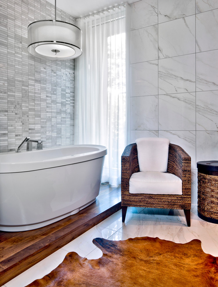 Foto de cuarto de baño contemporáneo con bañera exenta, baldosas y/o azulejos grises y paredes grises