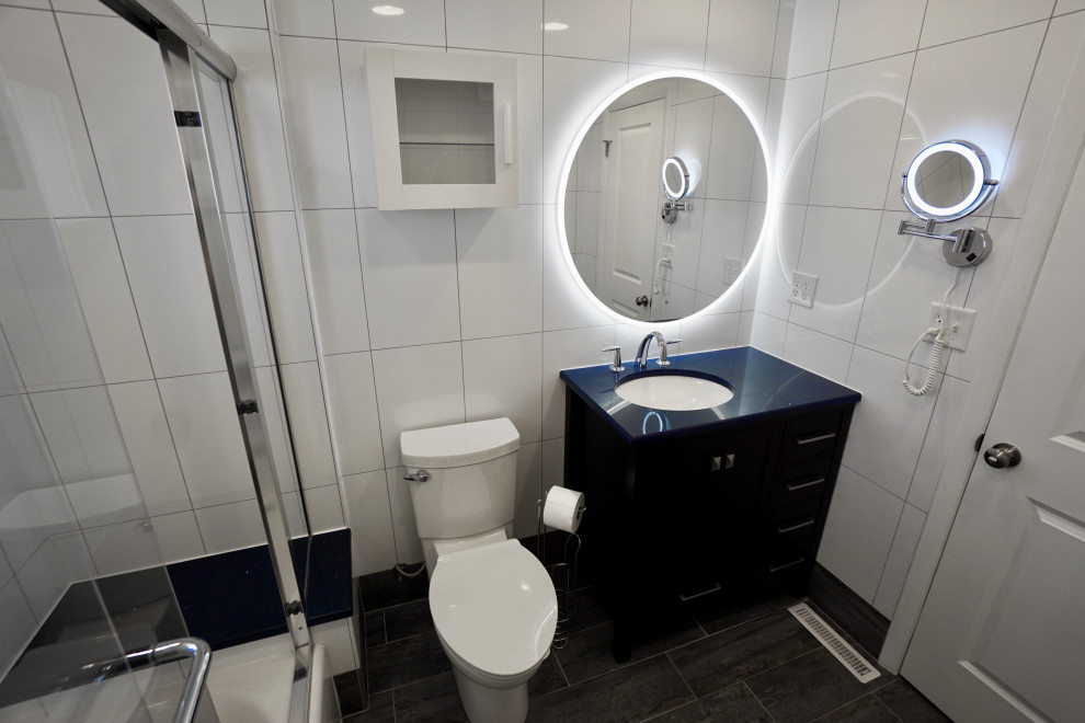 Idées déco pour une petite salle de bain principale contemporaine avec un placard à porte shaker, des portes de placard noires, une baignoire en alcôve, un combiné douche/baignoire, WC à poser, un carrelage blanc, des carreaux de céramique, un mur blanc, un sol en carrelage de céramique, un lavabo encastré, un plan de toilette en quartz, un sol gris, une cabine de douche à porte coulissante, un plan de toilette bleu, un banc de douche, meuble simple vasque et meuble-lavabo sur pied.