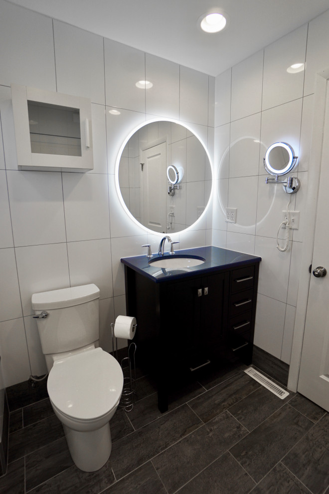 Пример оригинального дизайна: маленькая главная ванная комната в современном стиле с фасадами в стиле шейкер, черными фасадами, ванной в нише, душем над ванной, унитазом-моноблоком, белой плиткой, керамической плиткой, белыми стенами, полом из керамической плитки, врезной раковиной, столешницей из кварцита, серым полом, душем с раздвижными дверями, синей столешницей, сиденьем для душа, тумбой под одну раковину и напольной тумбой для на участке и в саду