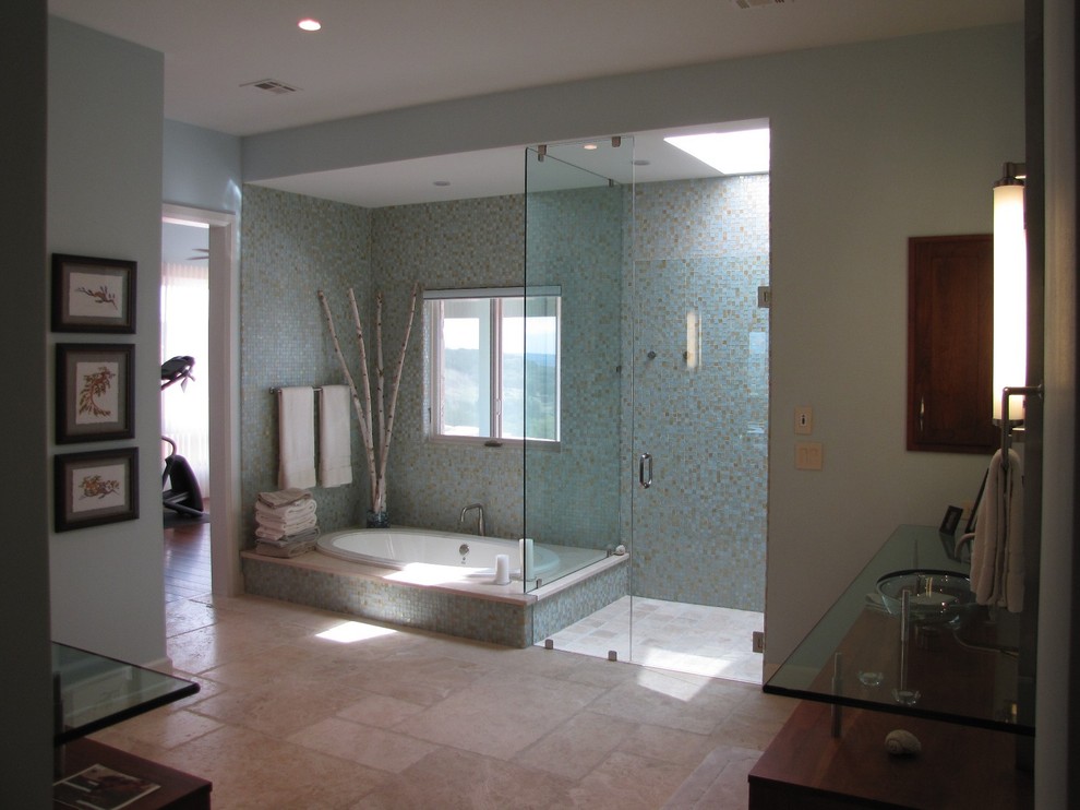 На фото: огромная главная ванная комната в стиле неоклассика (современная классика) с стеклянной столешницей, накладной ванной, угловым душем, синей плиткой, стеклянной плиткой, синими стенами и полом из известняка с