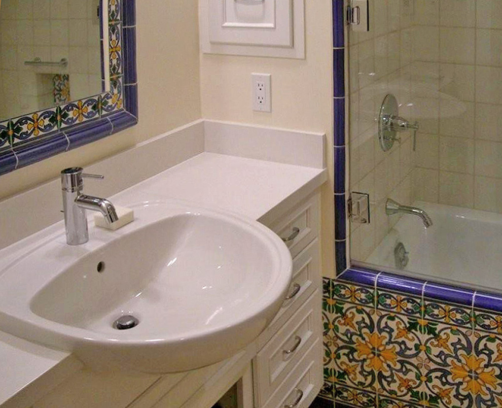 На фото: маленькая ванная комната в средиземноморском стиле с белыми фасадами, ванной в нише, душем над ванной, разноцветной плиткой, керамогранитной плиткой, белыми стенами, накладной раковиной, столешницей из искусственного кварца и фасадами с утопленной филенкой для на участке и в саду