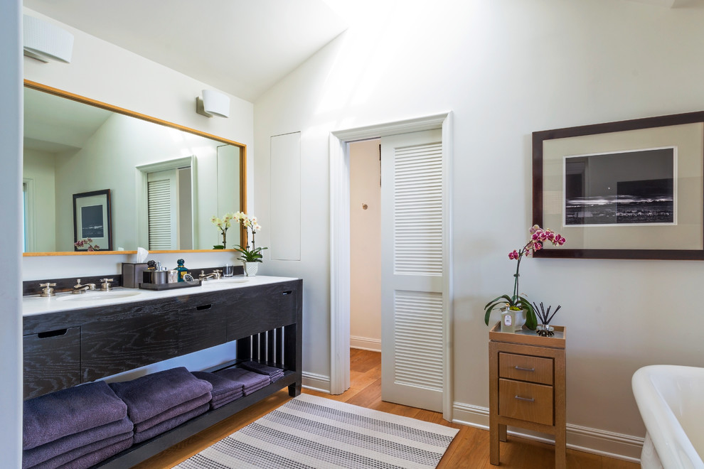 Imagen de cuarto de baño principal tropical grande con armarios tipo mueble, puertas de armario de madera en tonos medios y bañera exenta
