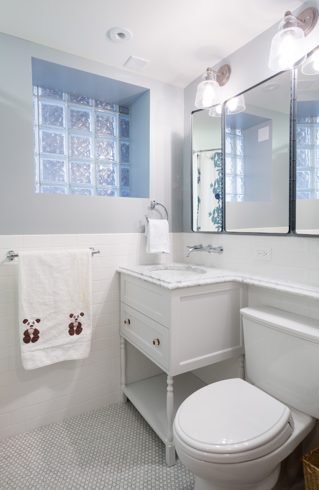 Inredning av ett klassiskt mellanstort badrum för barn, med ett undermonterad handfat, möbel-liknande, vita skåp, marmorbänkskiva, ett badkar i en alkov, en toalettstol med separat cisternkåpa, vit kakel, porslinskakel, blå väggar och mosaikgolv