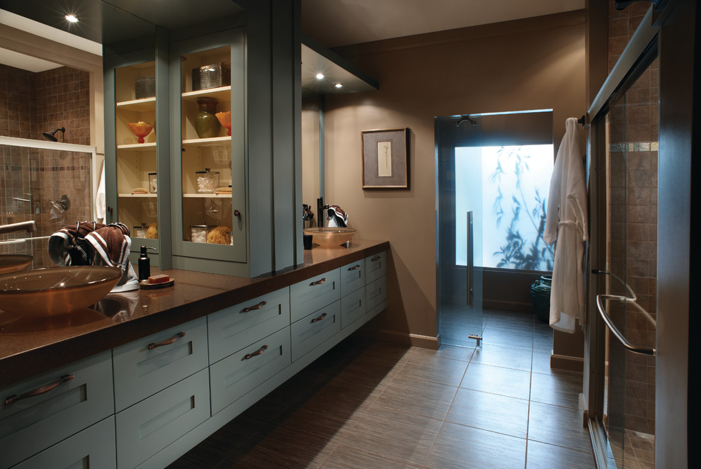 Diseño de cuarto de baño principal moderno grande con lavabo sobreencimera, armarios con paneles empotrados, puertas de armario azules, paredes marrones y suelo de madera en tonos medios