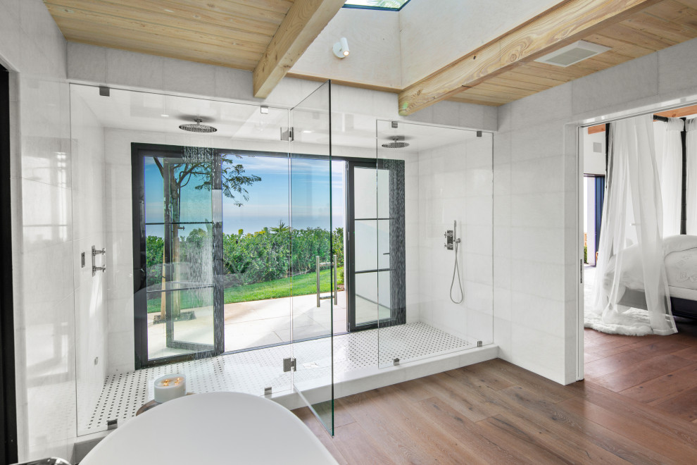 Badezimmer En Suite mit freistehender Badewanne, Doppeldusche, weißen Fliesen, braunem Holzboden, braunem Boden, Falttür-Duschabtrennung und Holzdecke in Los Angeles