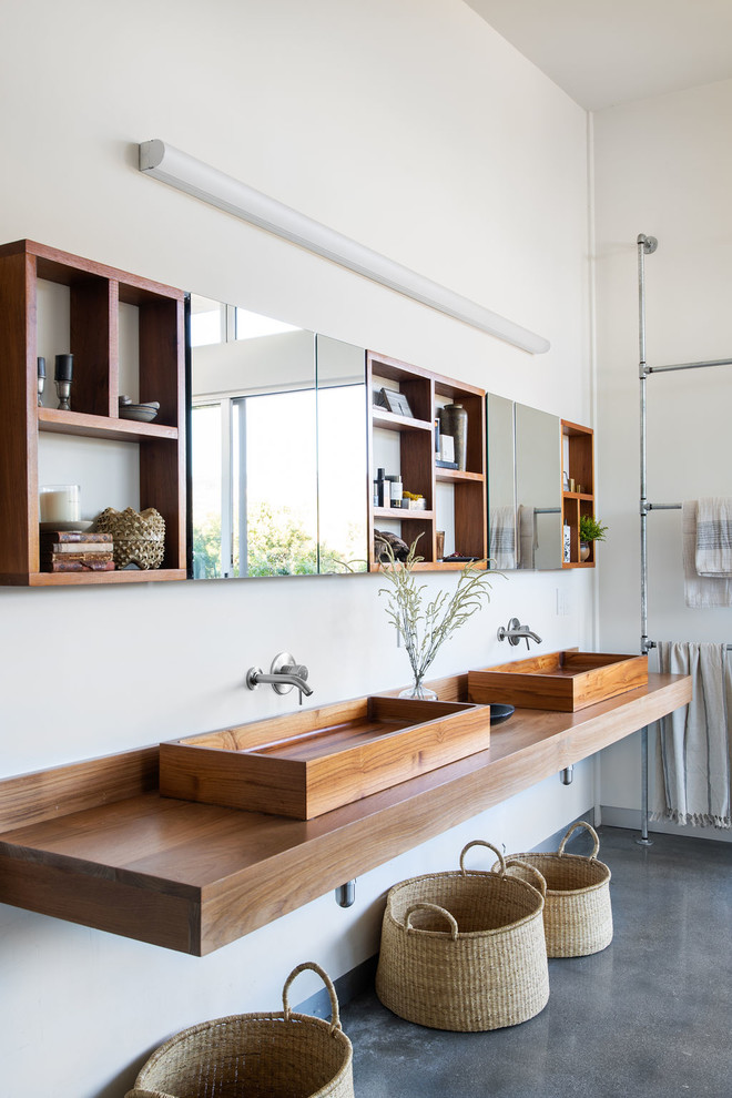 На фото: ванная комната в современном стиле с белыми стенами, бетонным полом, настольной раковиной, столешницей из дерева, серым полом и коричневой столешницей с