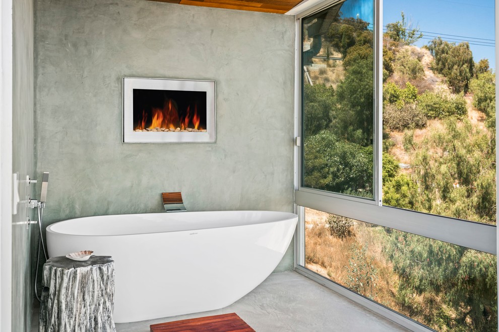 На фото: ванная комната в современном стиле с отдельно стоящей ванной, серыми стенами, бетонным полом и серым полом с