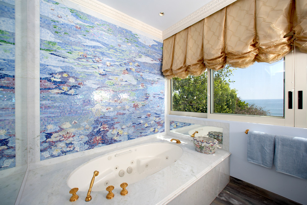 Idée de décoration pour une grande salle de bain principale tradition avec mosaïque, un carrelage multicolore, une baignoire d'angle, un mur bleu et un plan de toilette en marbre.