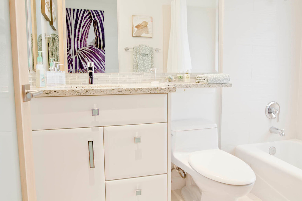 Exemple d'une salle de bain tendance avec un placard à porte plane, des portes de placard blanches, un plan de toilette en quartz modifié, un combiné douche/baignoire, un carrelage gris, un carrelage métro, un mur blanc et un sol en travertin.