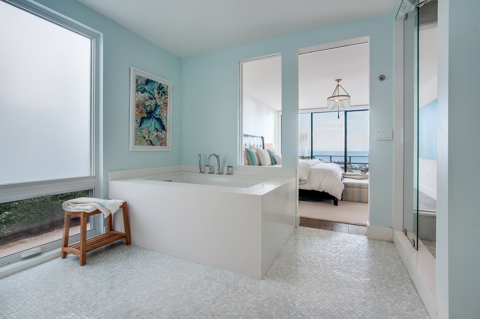 Modelo de cuarto de baño principal, marinero, sin sin inodoro, con armarios con paneles lisos, puertas de armario de madera clara, baldosas y/o azulejos de vidrio laminado, paredes azules, lavabo encastrado, encimera de cuarzo compacto, bañera encastrada sin remate y baldosas y/o azulejos blancos