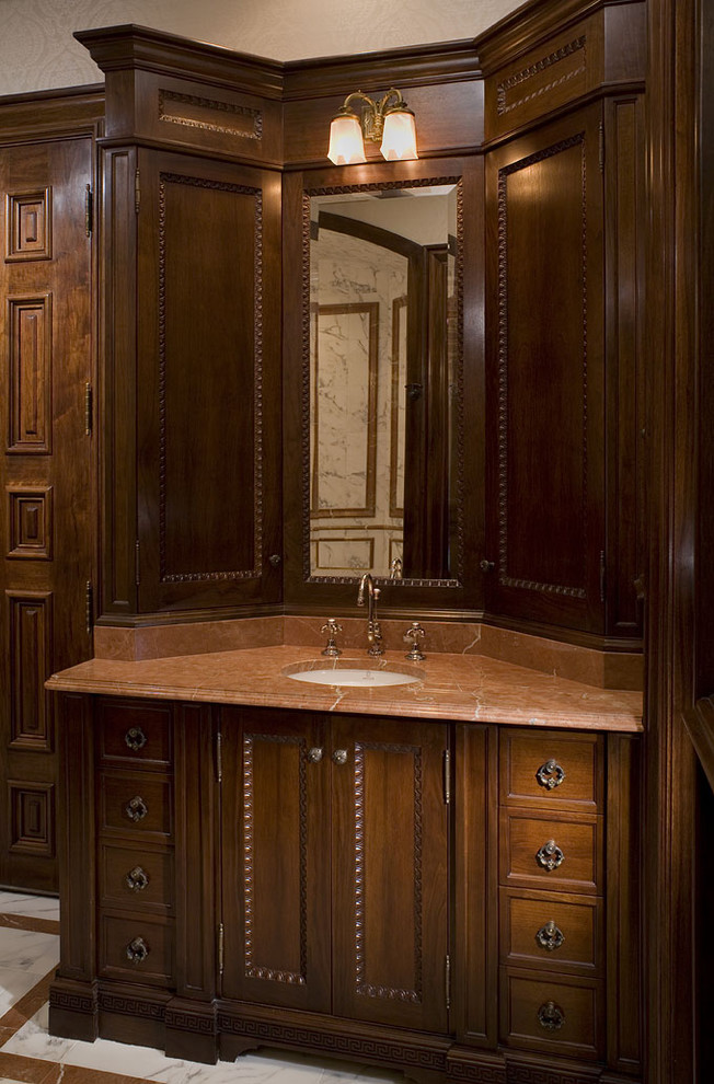 Ejemplo de cuarto de baño tradicional con lavabo bajoencimera, armarios con paneles empotrados y puertas de armario de madera oscura