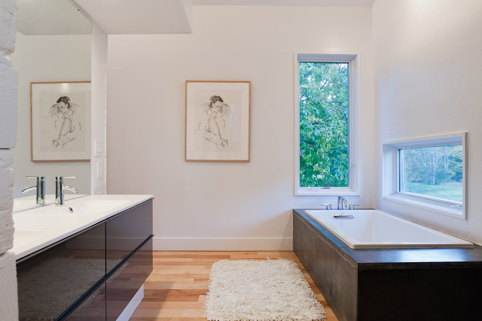 Example of a trendy corner bathtub design in Other with an integrated sink and flat-panel cabinets
