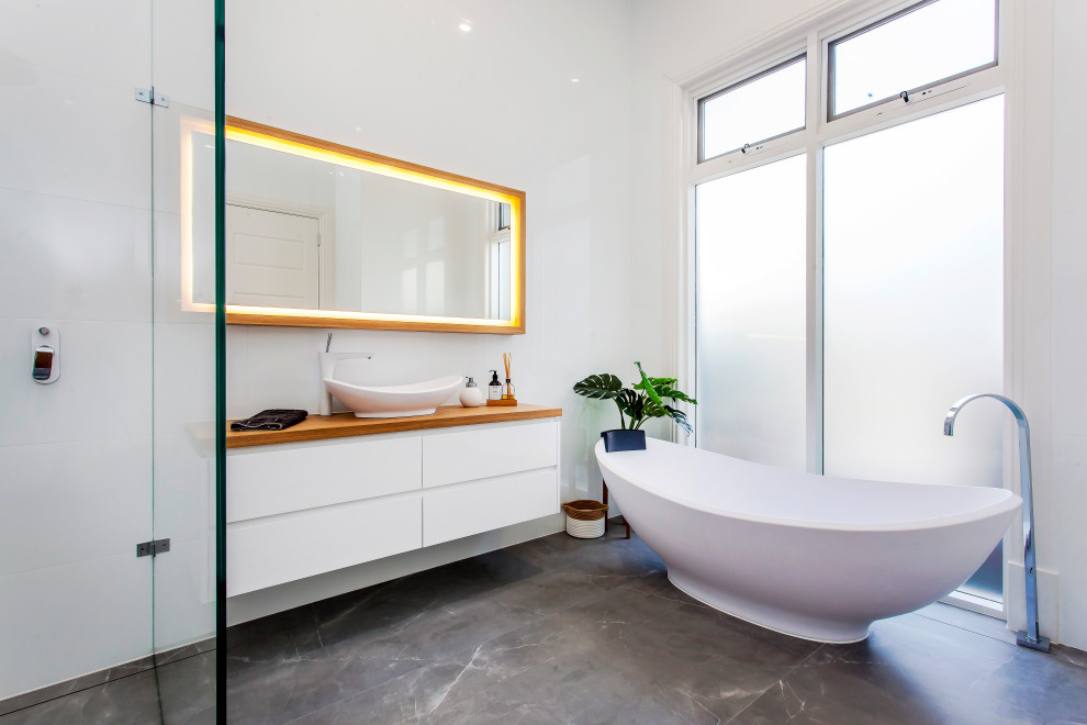 Medium sized contemporary ensuite bathroom in Adelaide with flat-panel cabinets, white cabinets, a freestanding bath, a built-in shower, white walls, a vessel sink, wooden worktops, grey floors, an open shower, brown worktops, a single sink and a floating vanity unit.