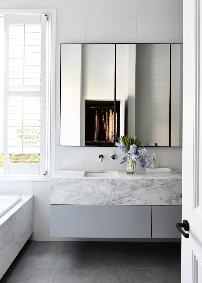 Modernes Badezimmer mit flächenbündigen Schrankfronten, grauen Schränken, Einbaubadewanne, weißer Wandfarbe, Unterbauwaschbecken und Marmor-Waschbecken/Waschtisch in Melbourne