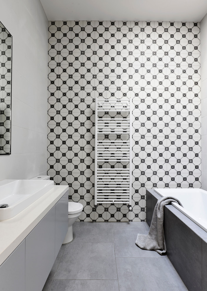 Bild på ett funkis badrum, med släta luckor, grå skåp, ett platsbyggt badkar, flerfärgade väggar och ett nedsänkt handfat