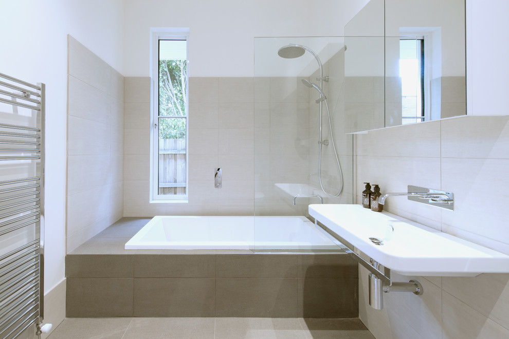 Exemple d'une salle de bain tendance de taille moyenne avec une baignoire posée, un combiné douche/baignoire, WC à poser, un carrelage beige, des carreaux de porcelaine, un mur blanc, un sol en carrelage de porcelaine et un lavabo suspendu.