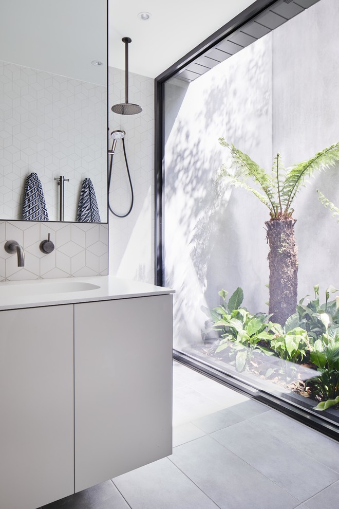 Modernes Badezimmer mit flächenbündigen Schrankfronten, grauen Schränken, weißen Fliesen, integriertem Waschbecken, grauem Boden und weißer Waschtischplatte in Melbourne