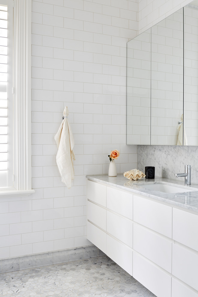 Idéer för mellanstora funkis vitt en-suite badrum, med vita skåp, vit kakel, tunnelbanekakel, vita väggar, marmorgolv, ett undermonterad handfat, marmorbänkskiva, grått golv och släta luckor