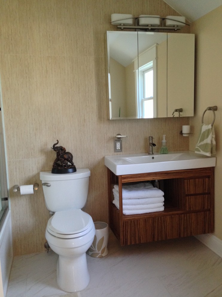Example of a mid-sized minimalist 3/4 beige tile and porcelain tile bathroom design in New York with an integrated sink, flat-panel cabinets, medium tone wood cabinets, solid surface countertops, a one-piece toilet and beige walls