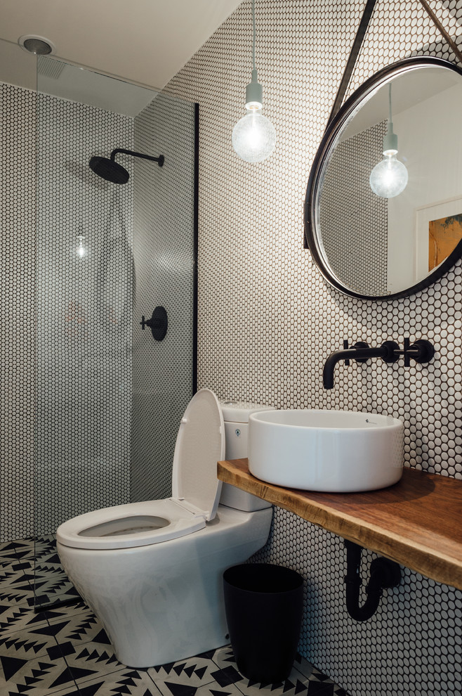 Exempel på ett litet 50 tals brun brunt badrum med dusch, med en öppen dusch, en toalettstol med hel cisternkåpa, svart och vit kakel, cementkakel, vita väggar, cementgolv, ett fristående handfat och träbänkskiva