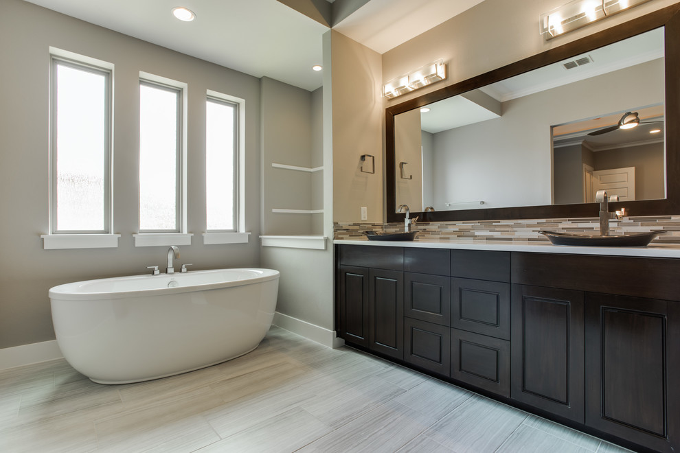 Freestanding bathtub - mid-sized transitional master beige tile and glass tile porcelain tile freestanding bathtub idea in Dallas with raised-panel cabinets, dark wood cabinets, a two-piece toilet, gray walls, an undermount sink and quartz countertops