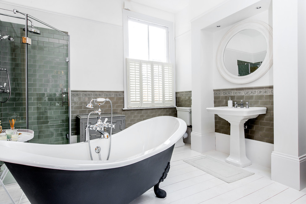 На фото: главная ванная комната в стиле неоклассика (современная классика) с ванной на ножках, угловым душем, серой плиткой, белыми стенами, деревянным полом и раковиной с пьедесталом с