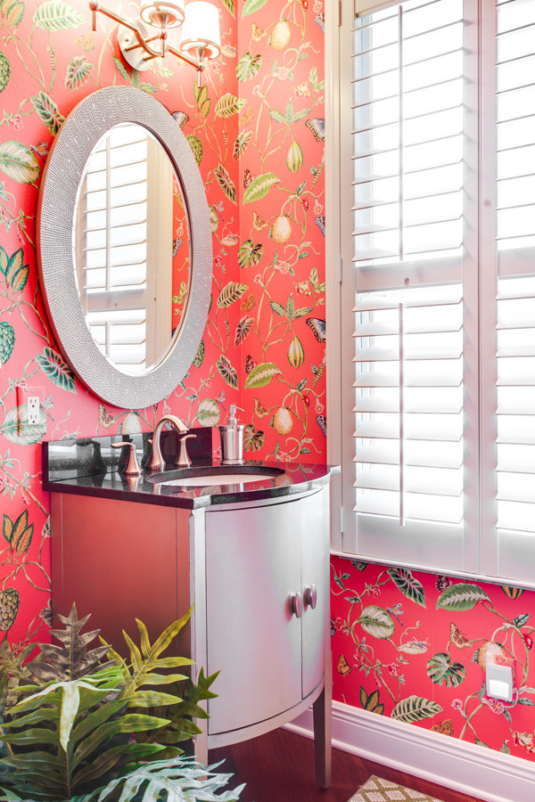 Aménagement d'une salle de bain classique de taille moyenne avec un lavabo encastré, des portes de placard noires, un plan de toilette en granite, un mur rose et un sol en bois brun.