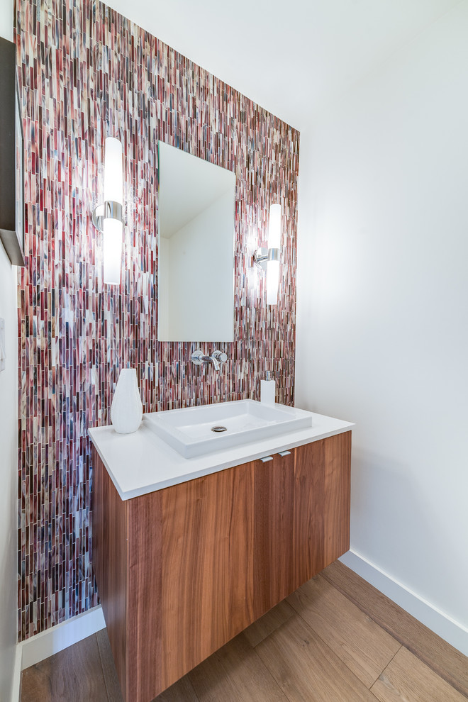 Bild på ett mellanstort 50 tals badrum med dusch, med släta luckor, skåp i mellenmörkt trä, flerfärgad kakel, vita väggar, glaskakel, ljust trägolv, ett fristående handfat, bänkskiva i akrylsten och brunt golv