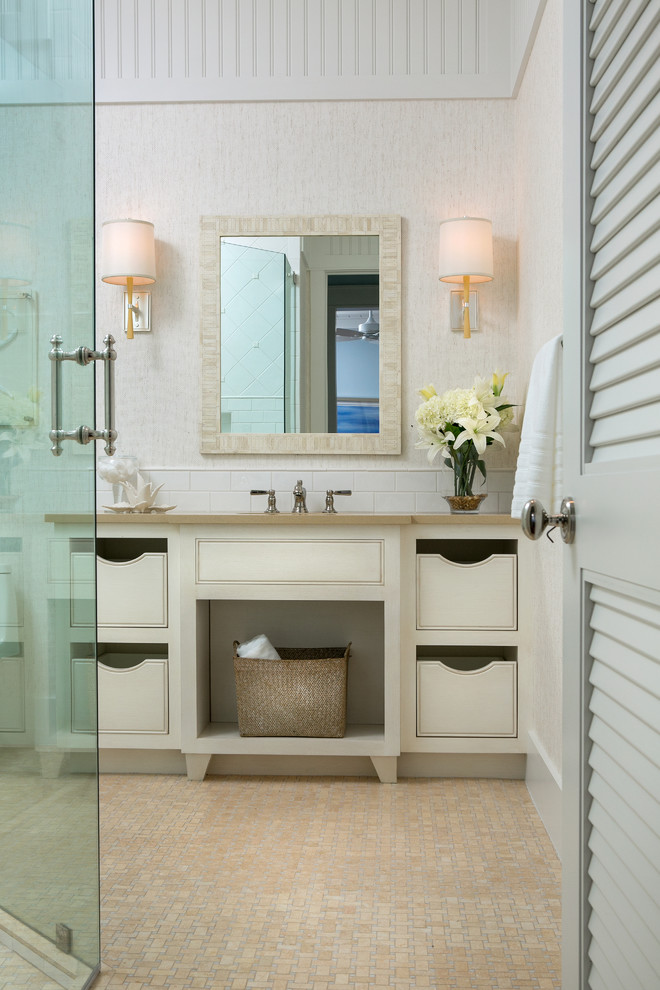 Exemple d'une grande salle de bain principale bord de mer avec des portes de placard beiges, un lavabo encastré, un sol beige et une cabine de douche à porte battante.