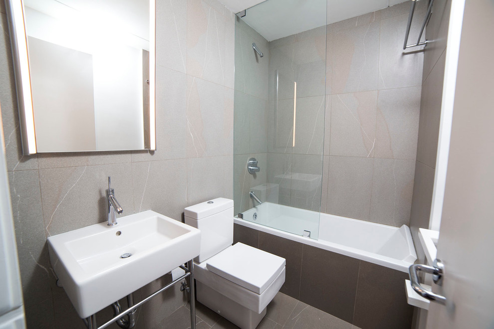 Exempel på ett mellanstort modernt badrum för barn, med ett badkar i en alkov, en dusch/badkar-kombination, en toalettstol med separat cisternkåpa, grå kakel, keramikplattor, grå väggar, klinkergolv i keramik, ett konsol handfat, bänkskiva i akrylsten, grått golv och med dusch som är öppen