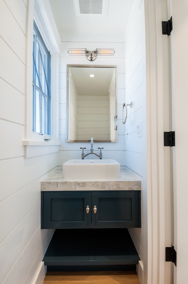 Idée de décoration pour une petite salle d'eau champêtre avec des portes de placard bleues, un mur blanc, un sol en bois brun et une vasque.