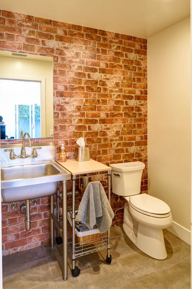 Immagine di una stanza da bagno con doccia industriale di medie dimensioni con ante grigie, piastrelle rosse, lastra di pietra, pareti rosse, pavimento in travertino, lavabo a colonna e top in acciaio inossidabile