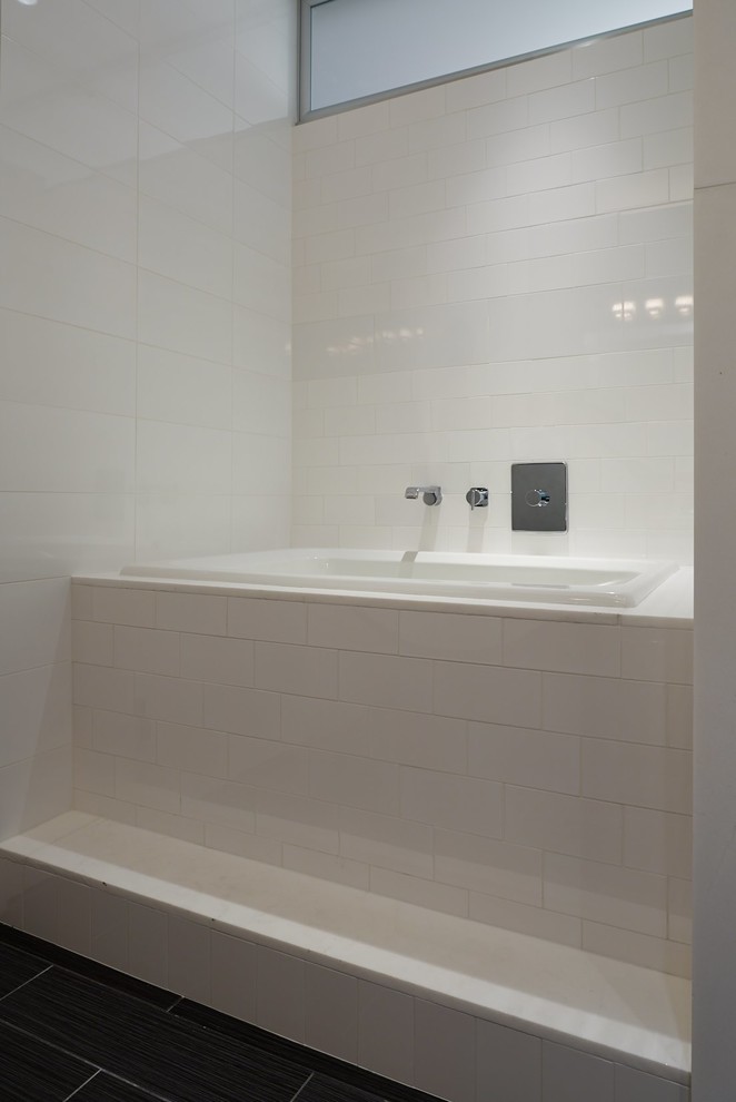 Inspiration for a medium sized contemporary ensuite bathroom in New York with flat-panel cabinets, a built-in bath, an alcove shower, a wall mounted toilet, white tiles, ceramic tiles, white walls, a vessel sink, a hinged door, porcelain flooring and black floors.