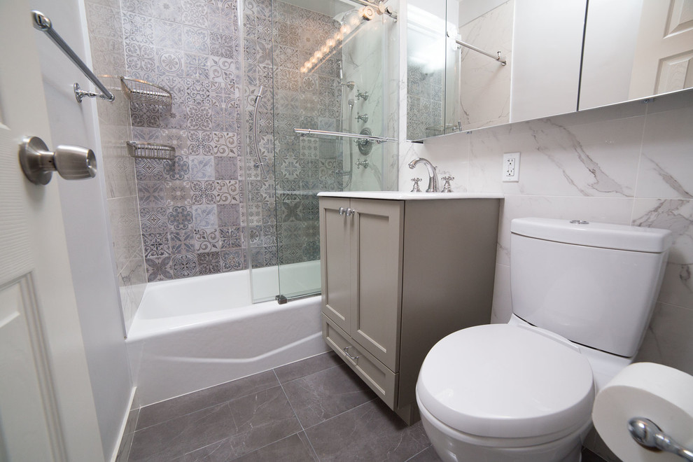 Cette image montre une petite salle d'eau traditionnelle avec un placard à porte shaker, des portes de placard grises, une baignoire en alcôve, un combiné douche/baignoire, WC séparés, un carrelage blanc, des carreaux de porcelaine, un mur blanc, un sol en carrelage de porcelaine, un lavabo intégré, un sol gris et une cabine de douche à porte coulissante.