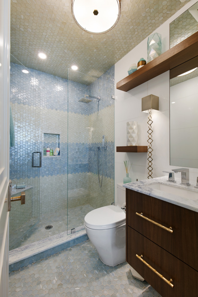 Пример оригинального дизайна: маленькая детская ванная комната в стиле фьюжн с плоскими фасадами, темными деревянными фасадами, полновстраиваемой ванной, душем в нише, раздельным унитазом, синей плиткой, стеклянной плиткой, белыми стенами, полом из мозаичной плитки, врезной раковиной, столешницей из кварцита, бежевым полом, душем с распашными дверями, синей столешницей, тумбой под одну раковину и подвесной тумбой для на участке и в саду