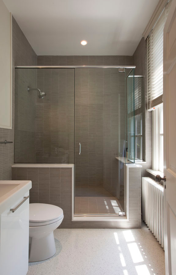 Corner shower - mid-sized modern master matchstick tile vinyl floor corner shower idea in New York with flat-panel cabinets, white cabinets, a one-piece toilet, gray walls, a drop-in sink and solid surface countertops