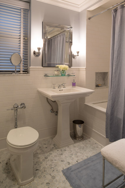 Bild på ett litet funkis en-suite badrum, med ett piedestal handfat, marmorbänkskiva, ett undermonterat badkar, en dusch/badkar-kombination, en toalettstol med hel cisternkåpa, vit kakel, tunnelbanekakel, blå väggar och marmorgolv